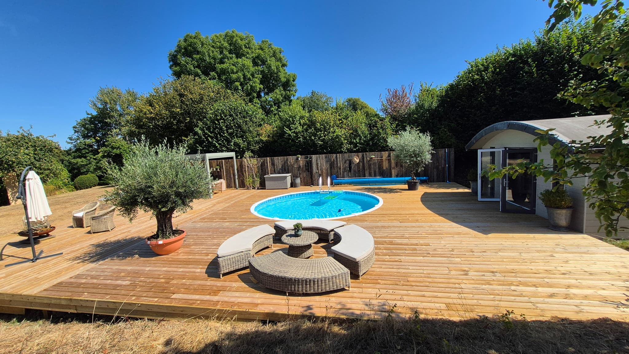 Completed 200 square metre timber pool deck with pergola and seating in Devon