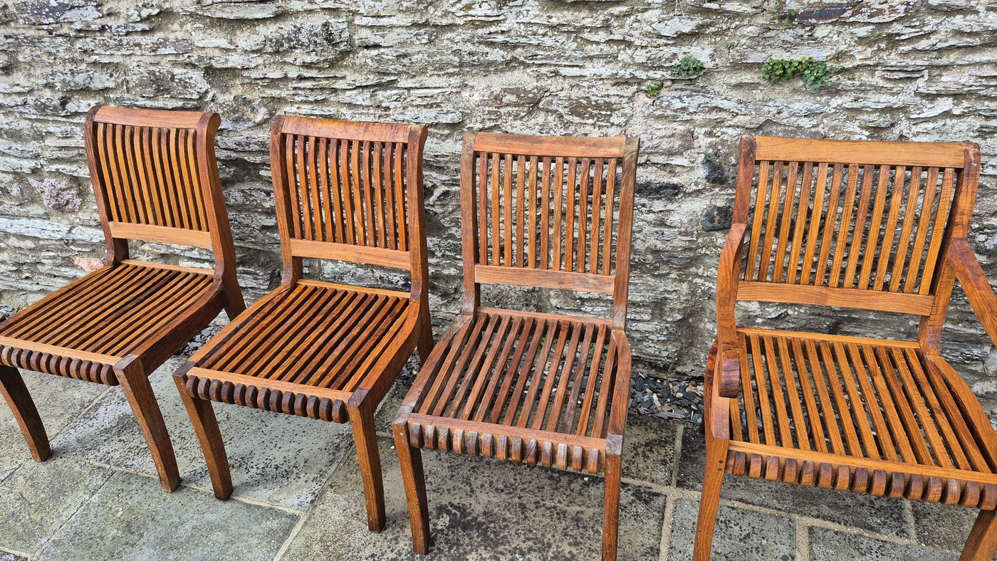 Teak chairs fully restored with rich warm oiled finish against stone wall