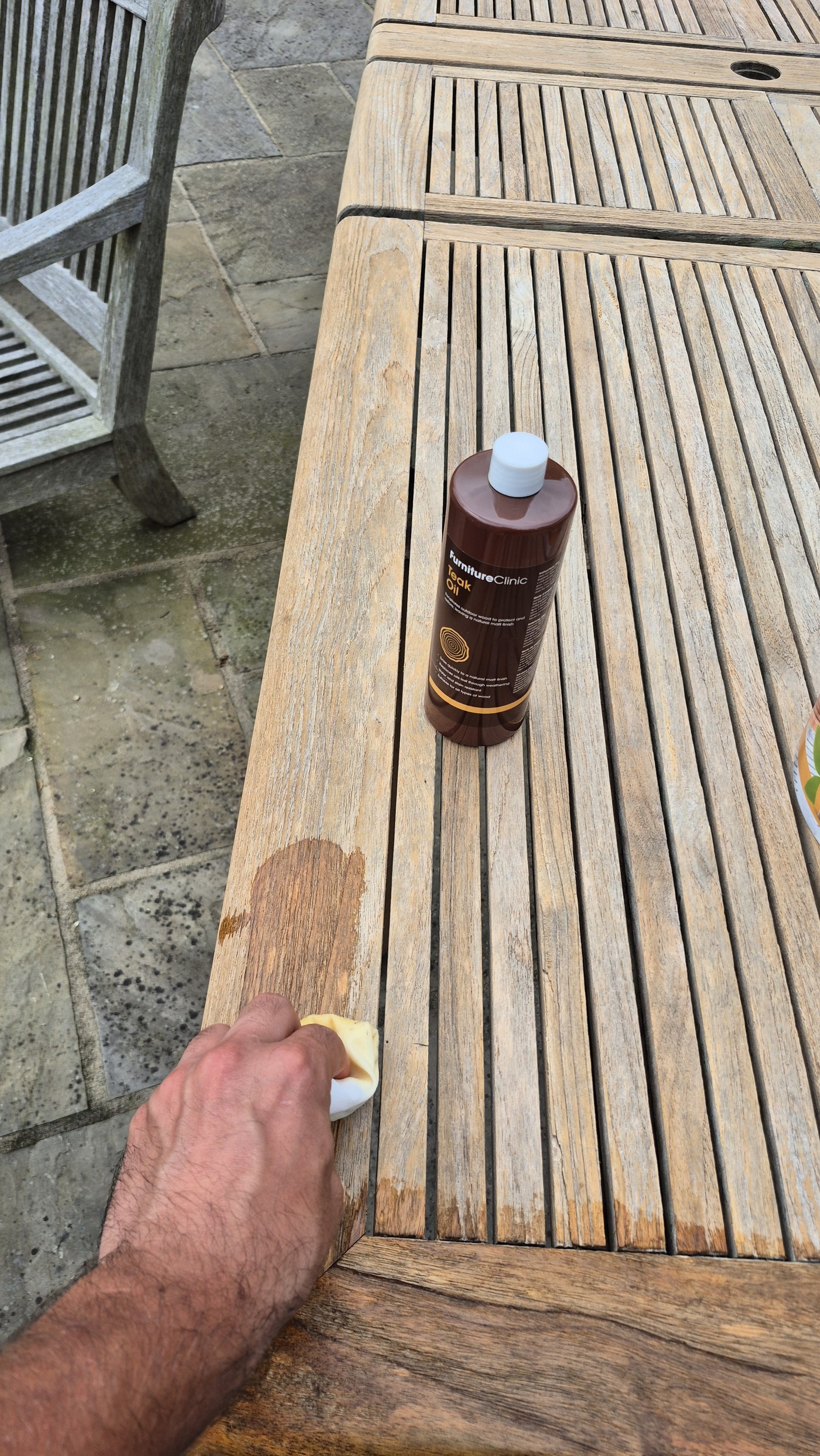 Applying teak oil by hand to restore the table's golden finish