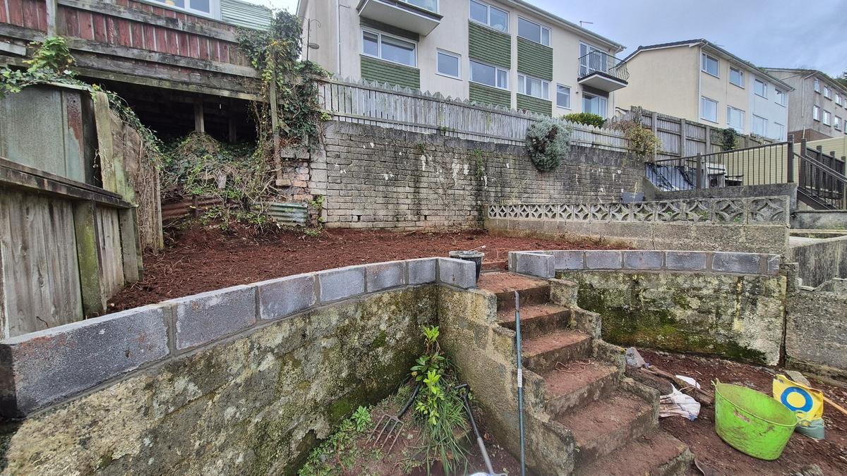 Garden cleared to bare earth showing retaining walls
